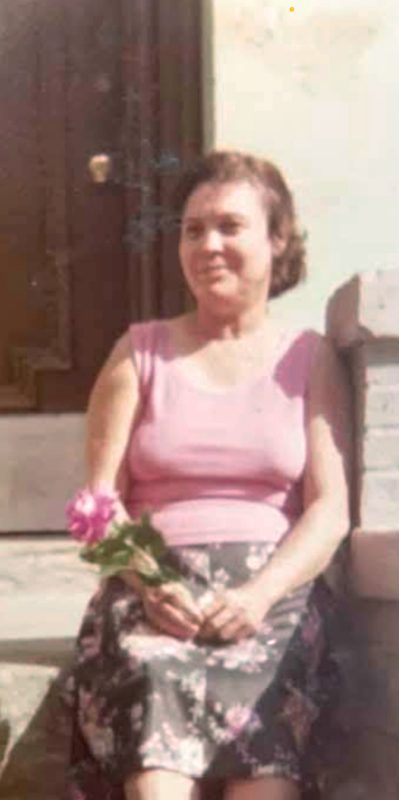 A woman sitting on steps and holding a pink flower.