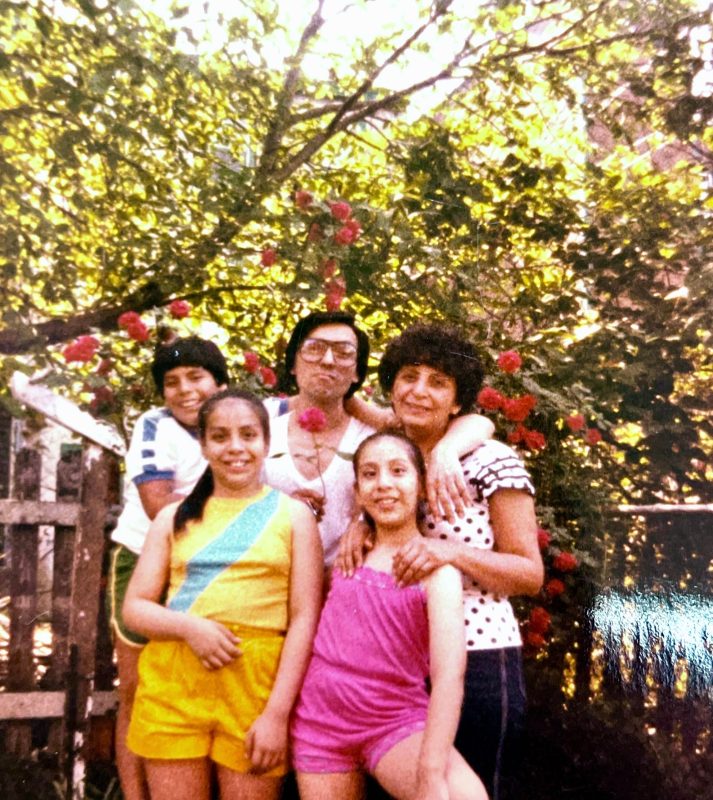 Portrait of two adults and three kids outside.