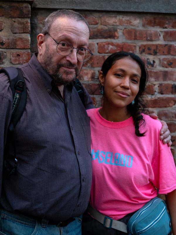 A man in a button down shirt and a woman wearing a pink t-shirt looking at the camera.